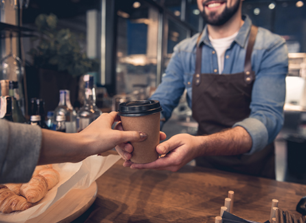 Barista handing woman a cup of coffee