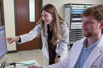 Female pharmacist pointing at computer screen