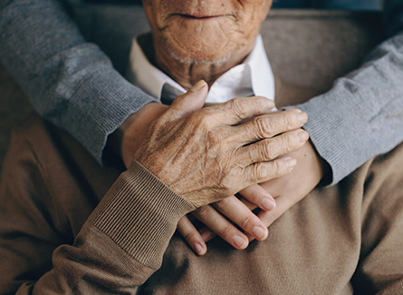 Woman holding mans hands over his heart.